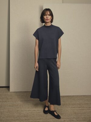 Model wearing MSCH Copenhagen Thamira knitted blue co-ord set featuring a high neck knit top with cap sleeves and wide leg culotte trousers.