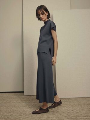 Side profile of model wearing MSCH Copenhagen Thamira knitted blue co-ord set featuring a high neck knit top with cap sleeves and wide leg culotte trousers.